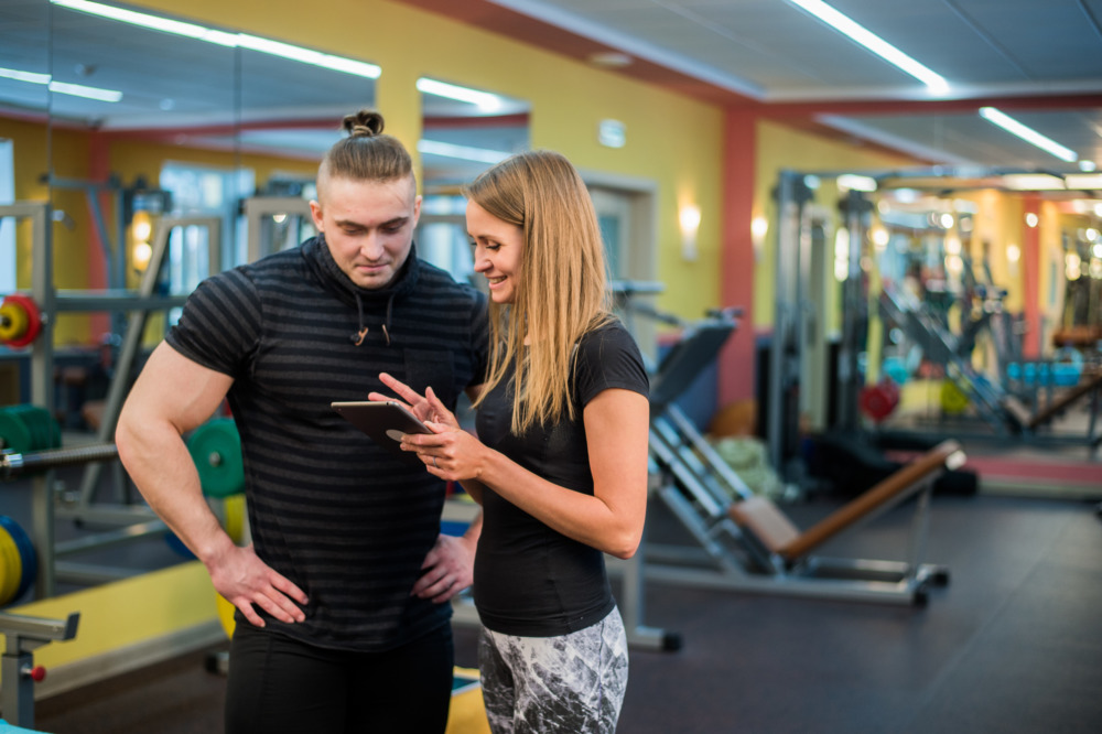 fit attractive young couple at a gym looking at a UDBLVCQ scaled