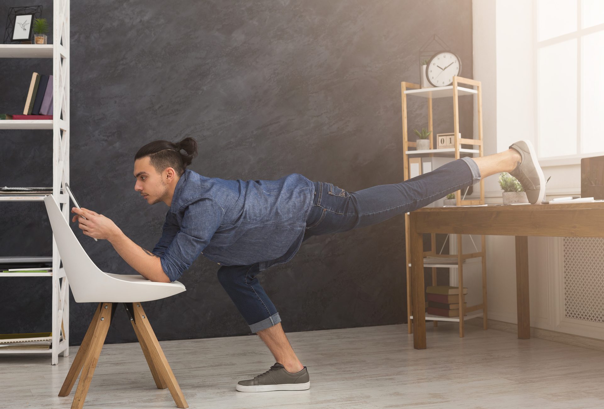 Mann macht Yoga-Pose im Büro und nutzt dabei ein Tablet